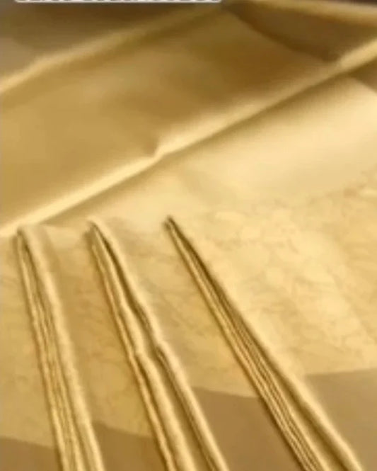 A close-up of a light beige or cream-colored fabric with a subtle woven pattern and three folded sections showing the texture and drape.