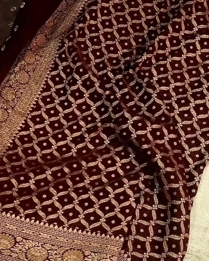 a close-up of a dark brown fabric with an intricate beige geometric lattice pattern and ornate woven borders.